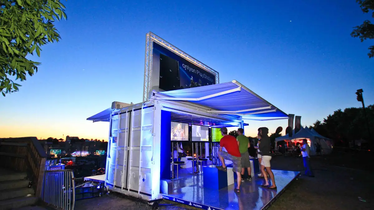 PlayStation outdoor game room lit blue at dusk with visitors playing