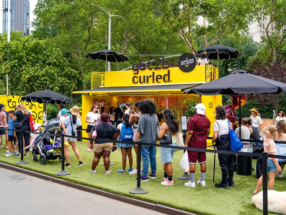 Got2B yellow mobile activation unit with an awning and a queue of visitors in a Manhattan park
