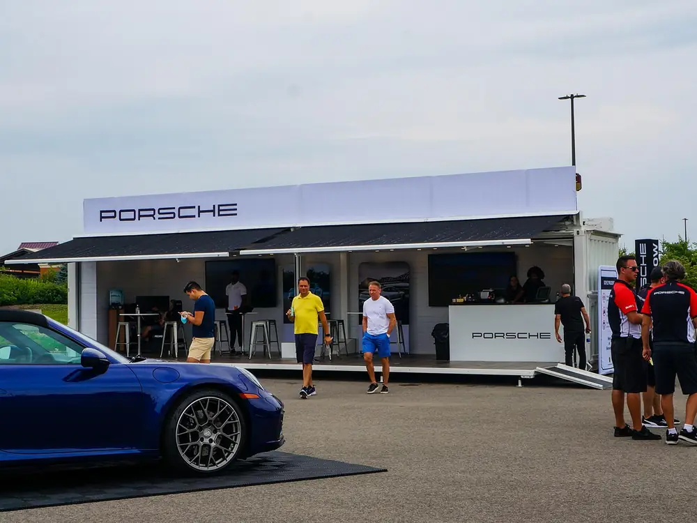 Porsche mobile showroom parked on a track with a car alongside